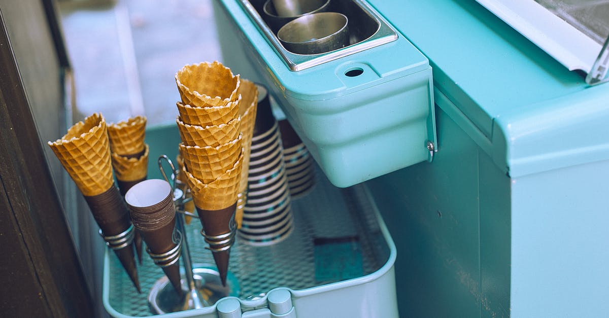 How can I extract palm sugar from a container? - From above of light blue ice cream cart equipped with metal glasses with scoop above basket with waffle cones and paper cups