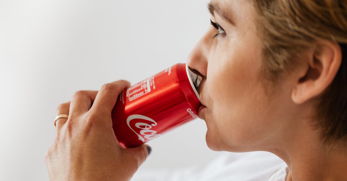 How can I get a syrupy "mouth-feel" in sugar-free syrup? - Side view of crop wistful female in casual wear and gold ring enjoying coke from red can while sitting near white wall and looking away
