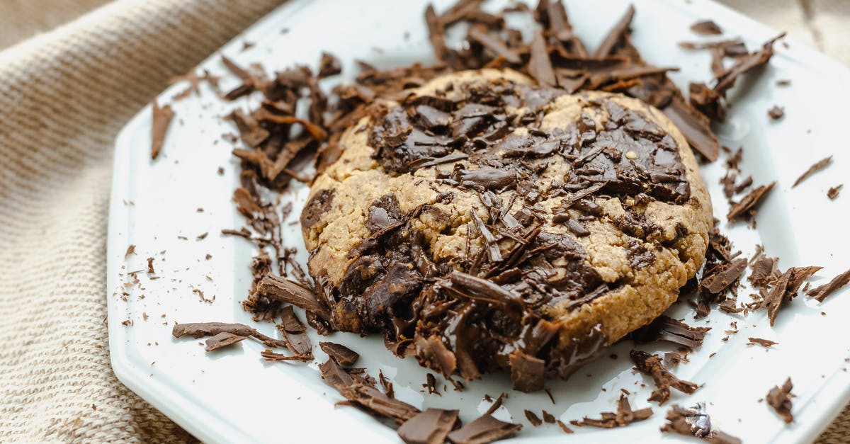 How can I get chewy chocolate chip cookies? - High angle of tasty homemade cookie with chocolate pieces on white ceramic plate