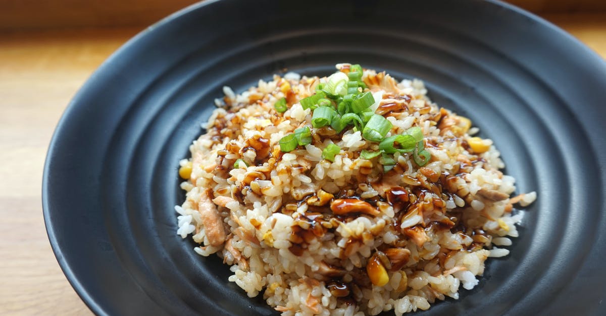 How can I judge the extra amount of water to use if I am cooking rice with extras in in my rice cooker? - Cooked Rice on Black Ceramic Plate