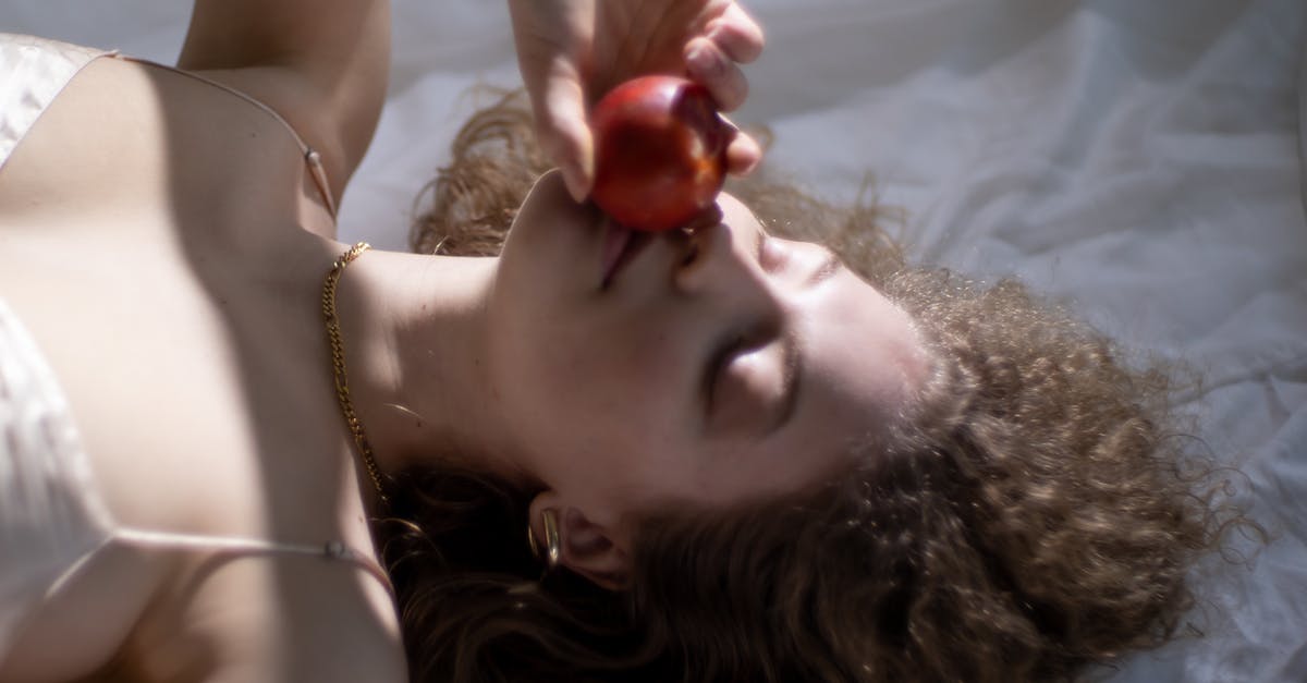How can I keep delicate food from sticking to the grill? - From above of young female with eyes closed smelling ripe red apple while lying on white fabric