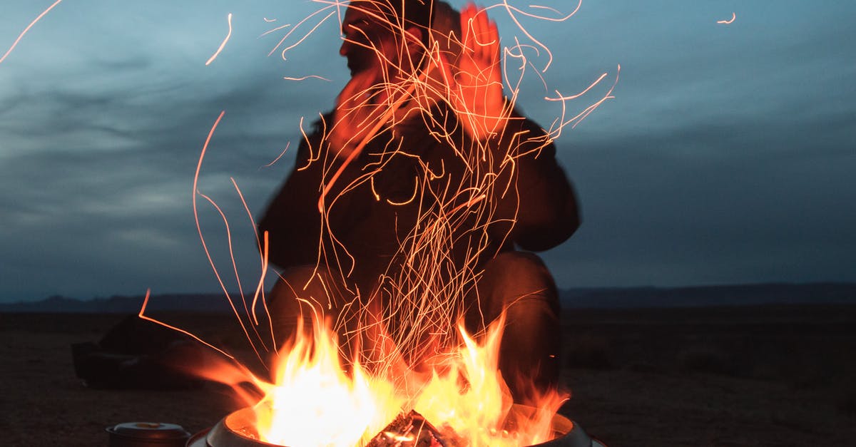 How can I light charcoal faster? - Man Sitting Facing Fire in Pot during Night