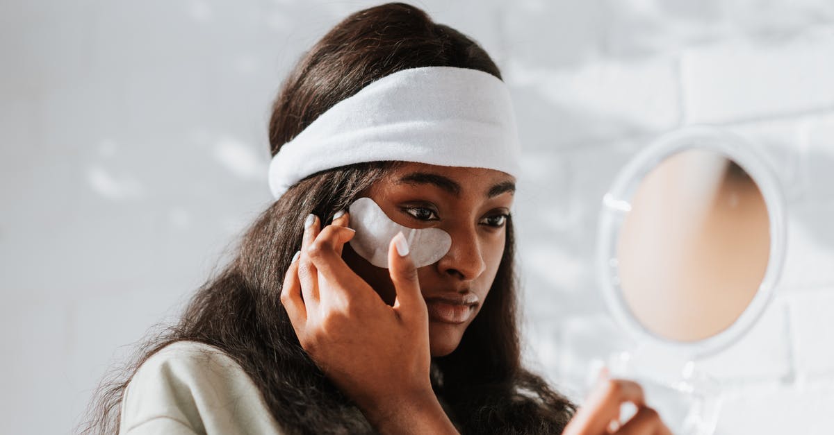 How can I make a silky smooth, rich mash? - Young African American female in headband applying eye patch on face while looking in mirror on white background