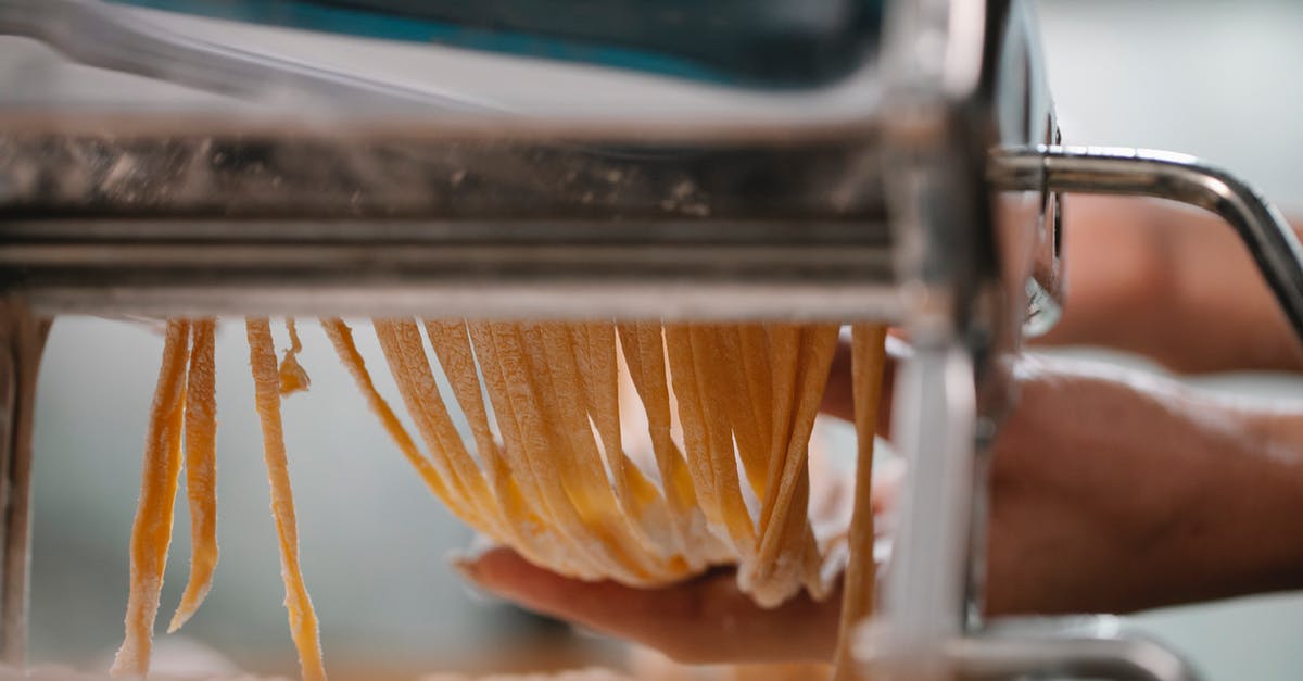 How can I make a super-thin, yet strong, calzone crust? - Crop anonymous female making fresh thin noodle while cutting dough in pasta machine