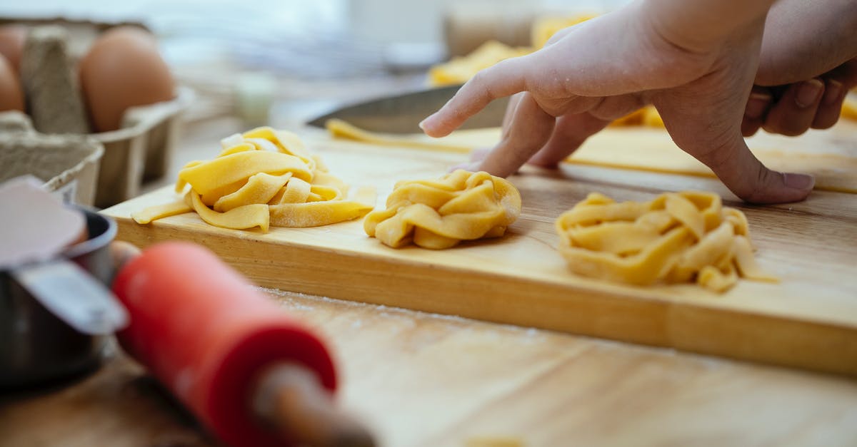 How can I make a super-thin, yet strong, calzone crust? - Faceless female making pasta cutting thin slice of dough into thin strips with sharp knife