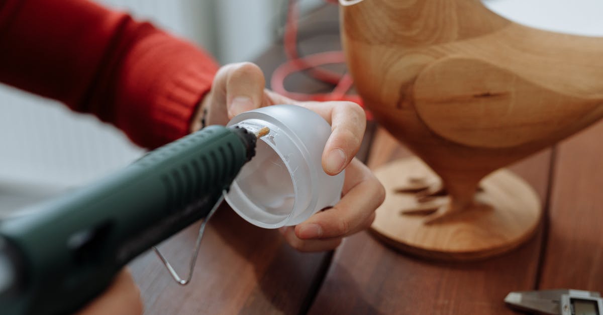 How can I make carving a chicken less messy? - A Person Applying a Glue on a Round Lid with a Glue Gun 