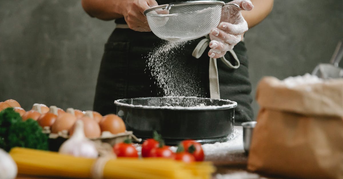 How can I make sifting easier? - Crop anonymous chef adding flour to baking dish while making meal with eggs cherry tomatoes and spaghetti