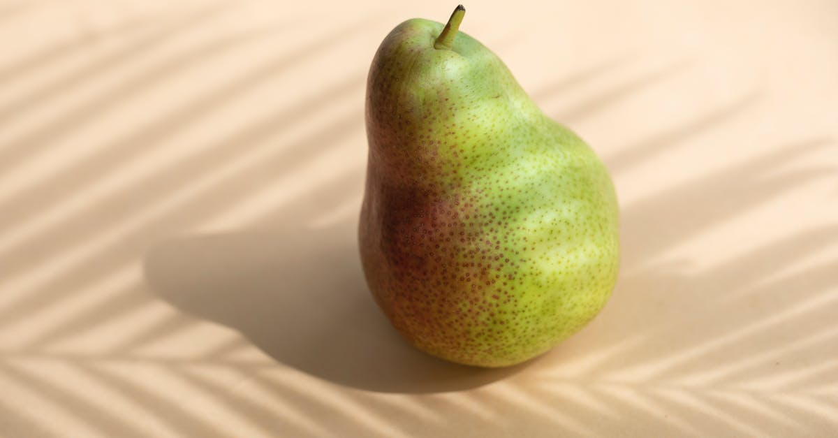 How can I minimize stirring when blending whole fruits? - High angle composition of whole fresh healthy delicious pear located on white surface in sun shadow of palm stem