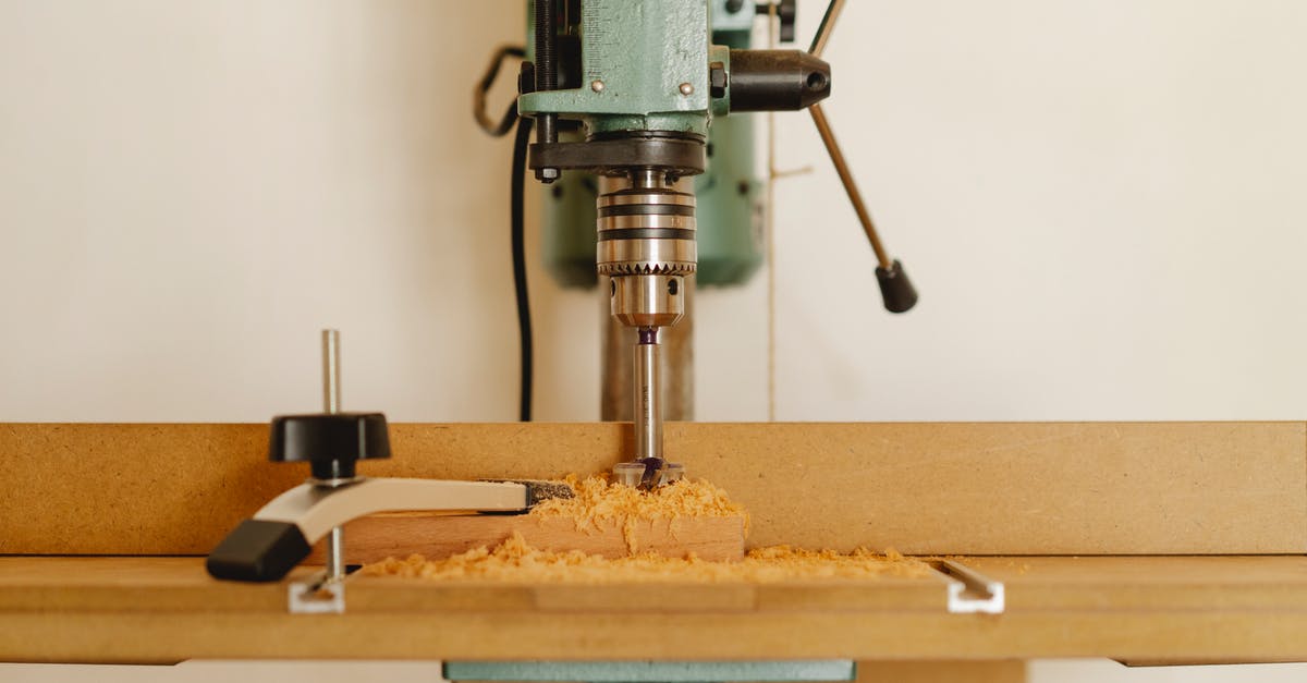 How can I safely improve my cutting technique - Professional drill machine for cutting wooden details near white wall in modern workshop
