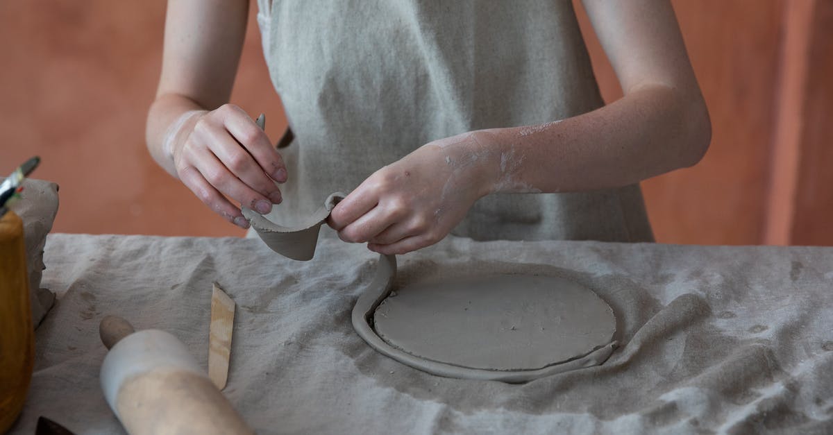 How can I safely improve my cutting technique - Unrecognizable skilled female master in apron standing near table with rolling pin and working with clay while making crockery during work in pottery workshop with blurred background