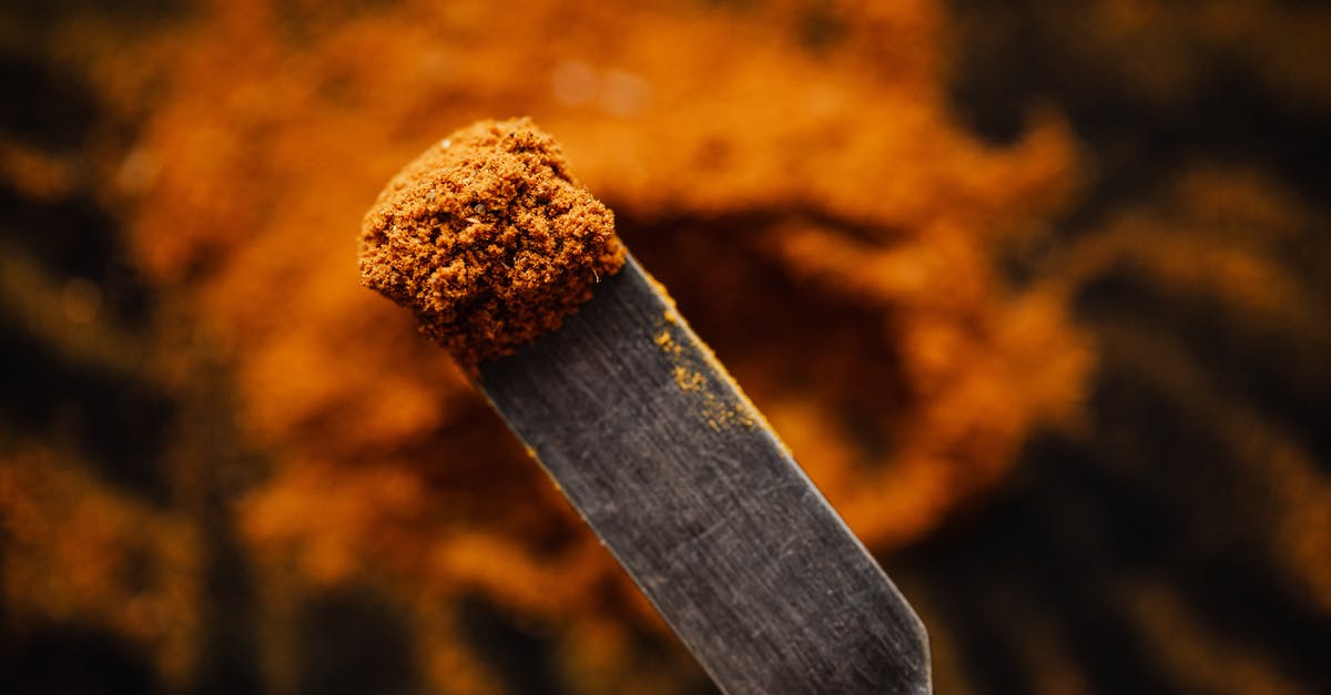 How can I spice up ground beef without using pepper? - Closeup spatula with sample of ground paprika taken from heap in dark barn