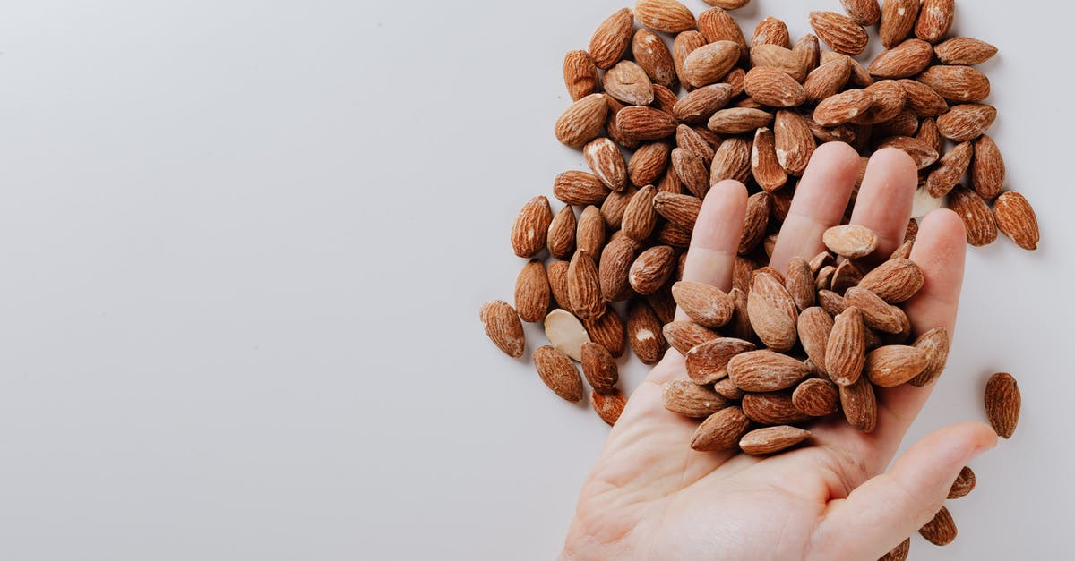 How can I take apart almonds? - From above of anonymous male taking tasty organic almonds from pile of nuts placed on white background isolated illustrating healthy food concept