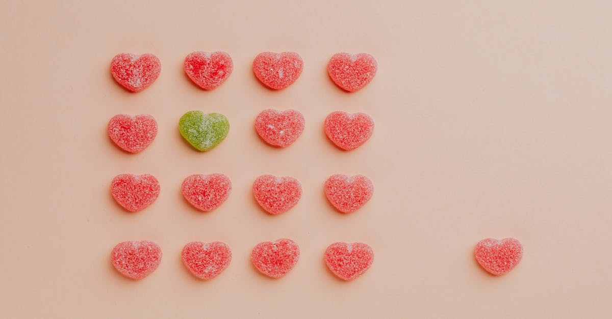 How can I tell the difference between unmarked sugar and stevia? - Top view of delicious sprinkled jelly sweets composed in lines with one candy aside on pink backdrop in candy shop