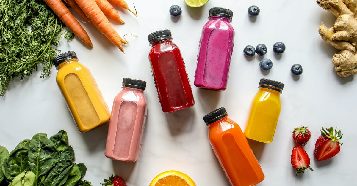 How can I thicken my smoothie without frozen ingredients? - Colorful Bottles with Smoothies Beside Carrots, Ginger, Leaves and Berries