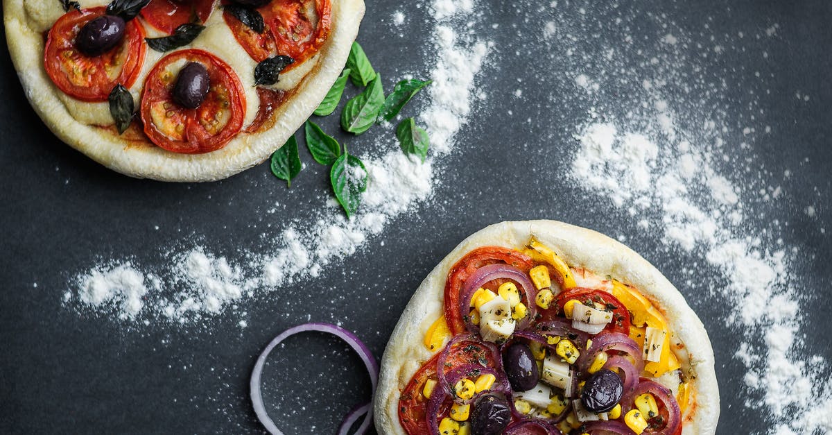 How can I use corn meal more efficiently when making pizzas? - Pizza with tomatoes and cheese on table with flour