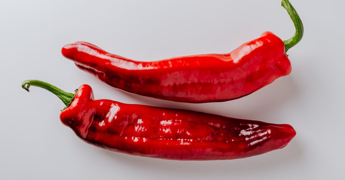 How can I wash down spicy food? - From above of pair of hot chili peppers with green sprouts and smooth surface put on white table