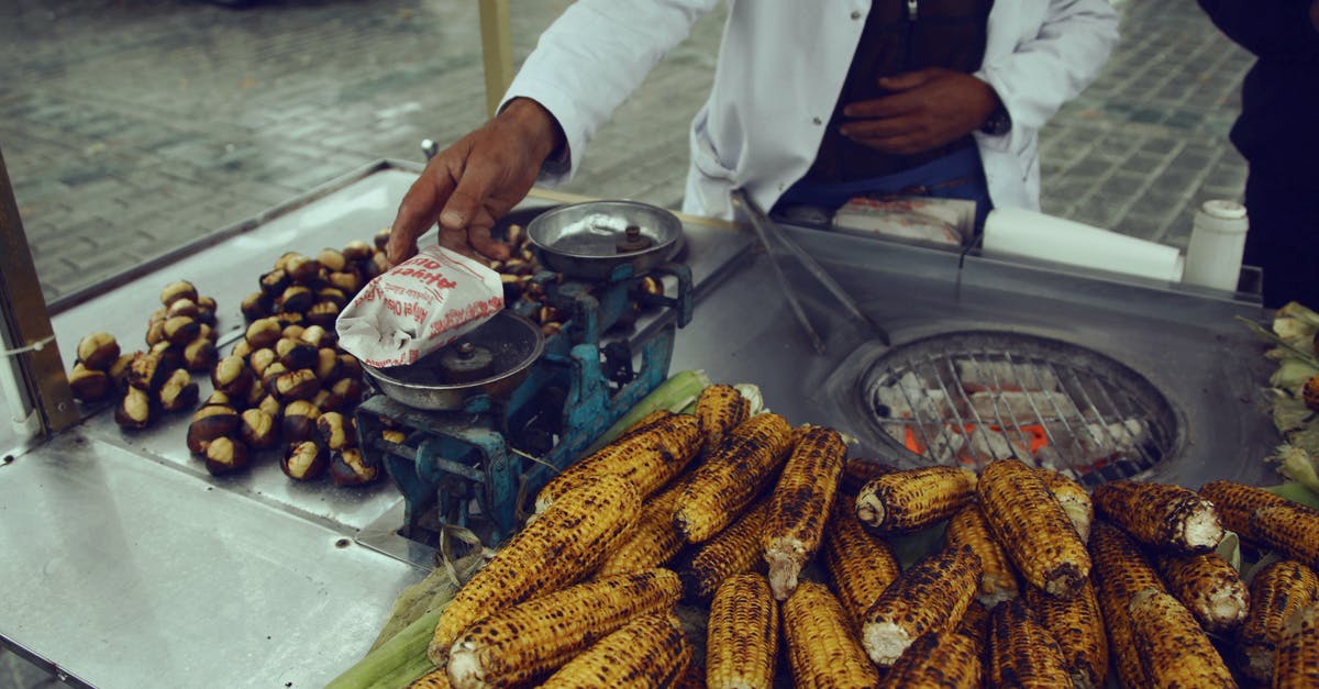 How can one cook corn on an open grill? [duplicate] - Unrecognizable ethnic person selling roasted corn and chestnuts in street