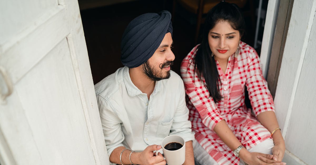 How can you tell when flour has gone off? - From above of good looking Indian wife listening to husband sharing news with cup of coffee in hand while both sitting at doorstep of house