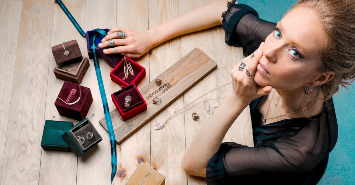 How did I strip the patina off my wok? - From above serious businesswoman looking up at camera while sitting at wooden table with small jewelry boxes with bijouterie and decorating with ribbon as present