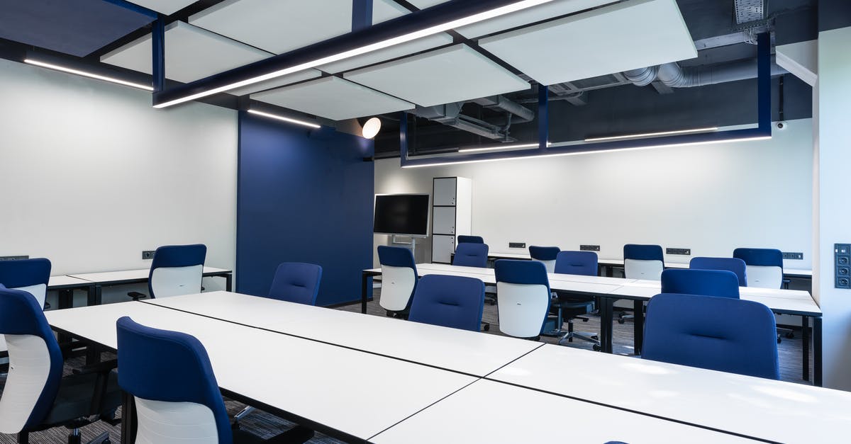 How do baking supply companies blanch their hazelnuts? - Interior of modern spacious workspace with long white tables and blue armchairs placed near monitor with black screen in business center