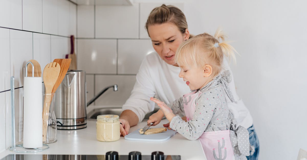 How do cooking utensils remain safe for use? - Woman in White Sweater Looking at a Girl in Apron Holding Knife