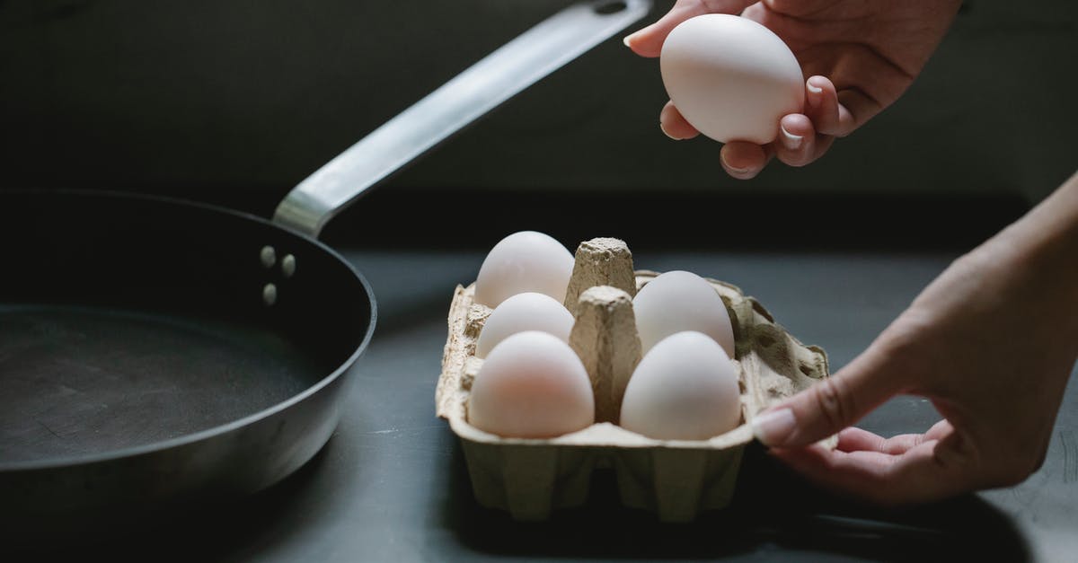 How do I accurately take a chicken thigh's temperature? - High angle of crop anonymous housewife taking raw chicken egg from paper container for preparing breakfast in kitchen