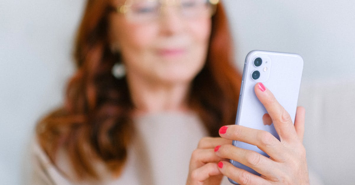 How do I age ginger? - Crop aged redhead female in eyeglasses using contemporary mobile phone while surfing internet in soft focus