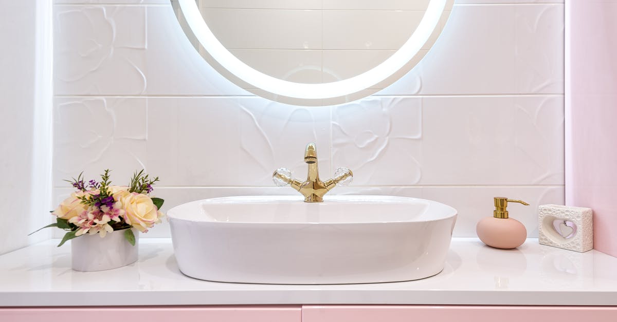 How do I clean the bottom of a porcelain pan? - Interior of modern bathroom with luminous mirror hanging under sink with faucet near blooming flowers and soap