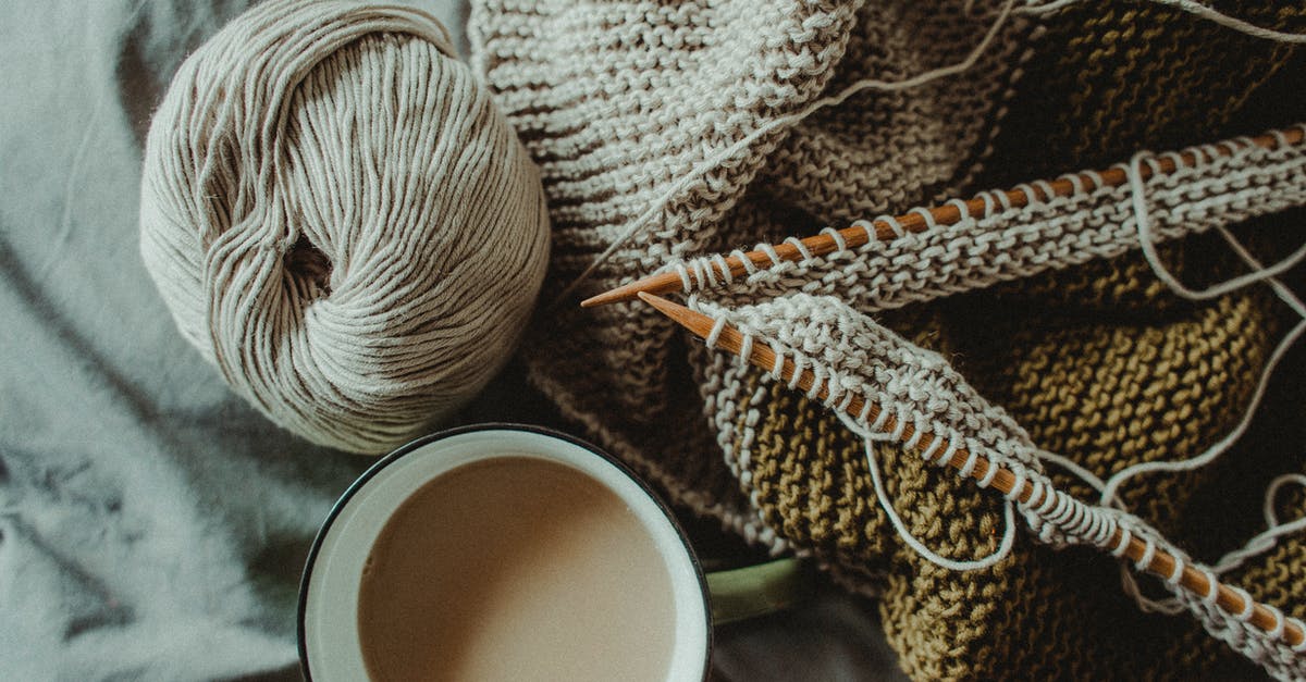 How do I create spherical coffee? - From above of cup of hot coffee placed on bed with handmade knitted plaid with needles and wool yarn