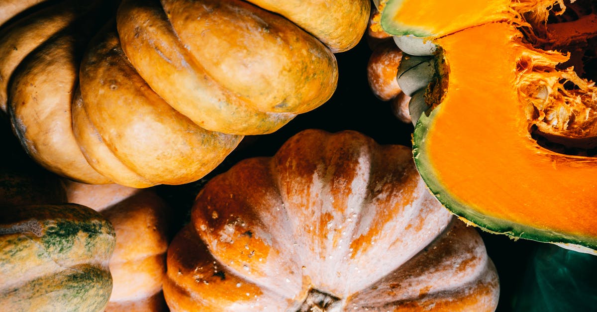 How do I cut an acorn squash? - Ripe organic pumpkins heaped on plastic surface