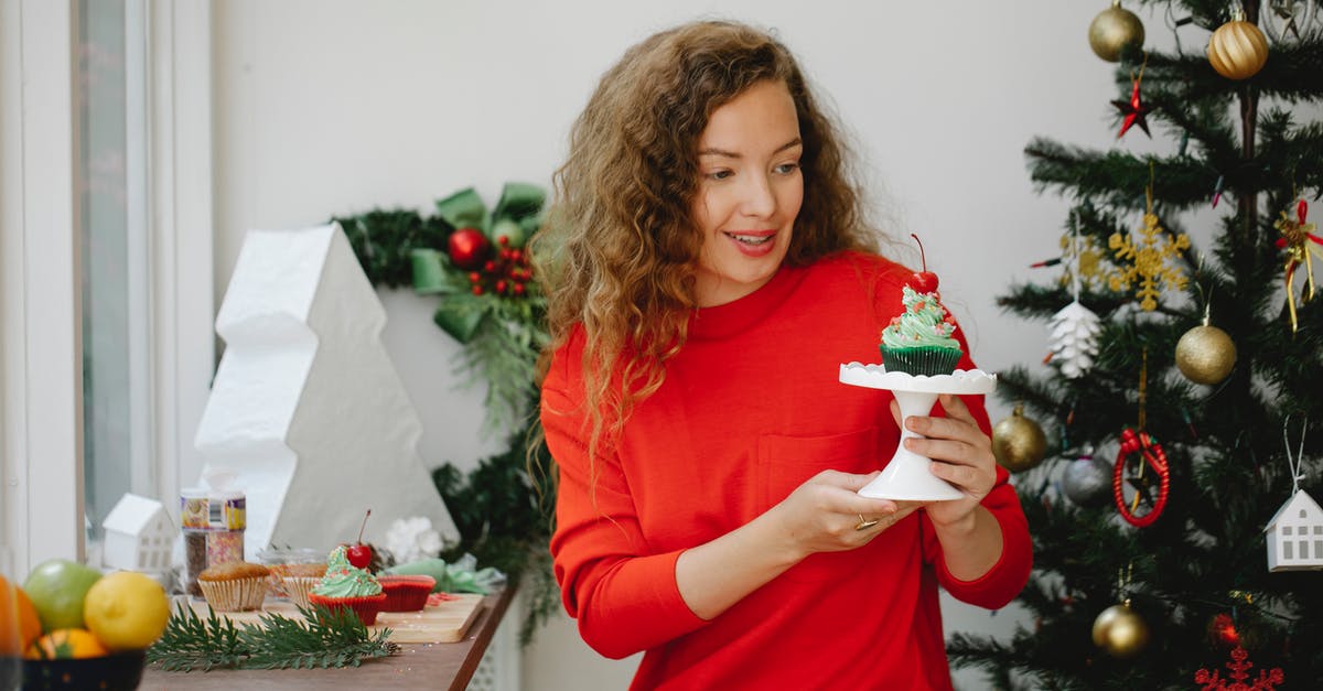 How do I get my homemade english muffins to taste like english muffins? - Cheerful young woman holding stand with cupcake sitting beside decorated fir tree at home