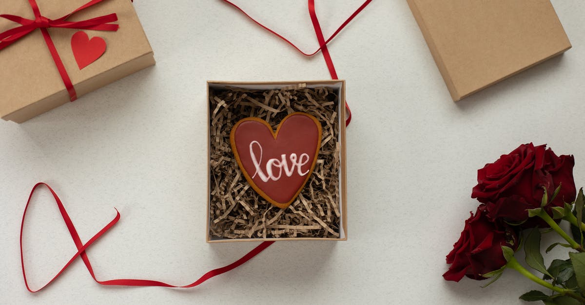 How do I get the filling inside pâte à choux? - Top view of heart shaped cookie with Love word in box with decorative paper filling [laced on gray background near gift boxes with red ribbons and bouquet of roses