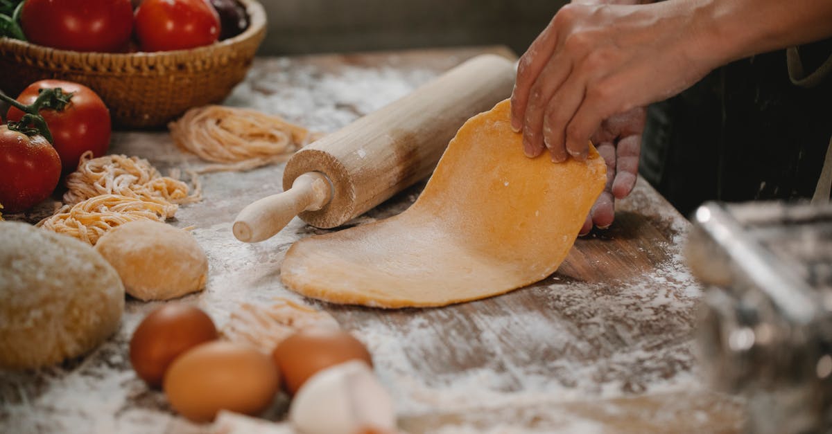 How do I hand-roll homemade pasta made with egg? - Anonymous woman making dough for spaghetti standing at table with vegetables and eggs