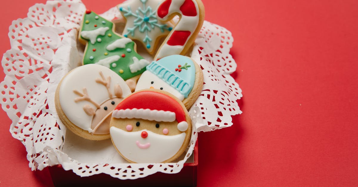 How do I keep Glaze for Gingerbread cookies translucent - High angle of small box with Christmas biscuits decorated with colourful icing on white doily