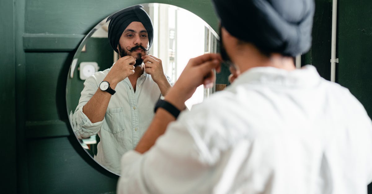How do I make authentic Russian black bread? - Back view of young Indian male with twisted mustache wearing denim shirt and turban taking care of beard standing against mirror on wall during daytime