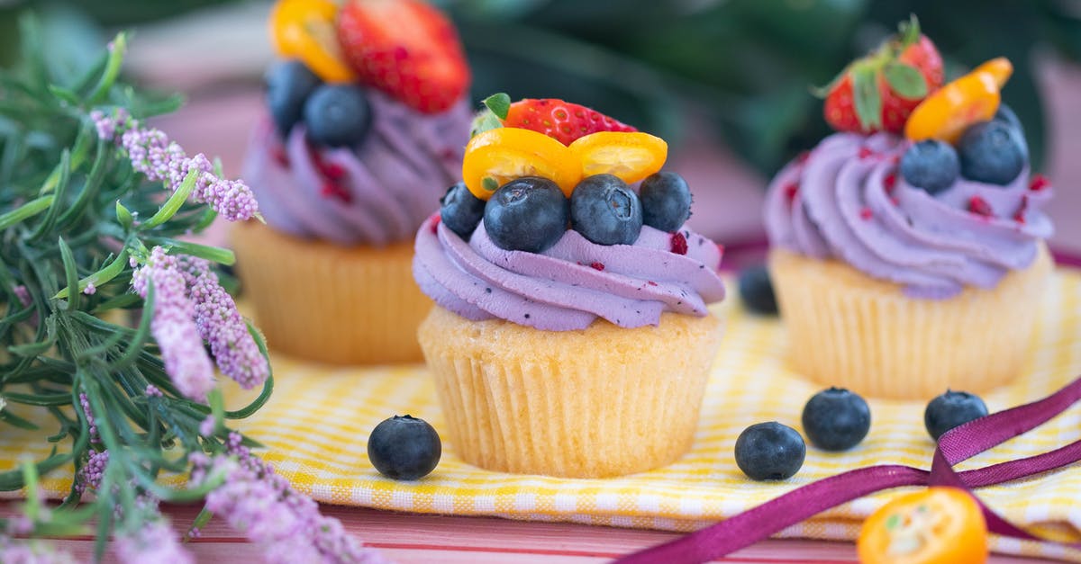 How do I make meringue using a whipped cream charger? - Tasty sweet cupcakes decorated with fresh blueberries and strawberries served on table with flowers