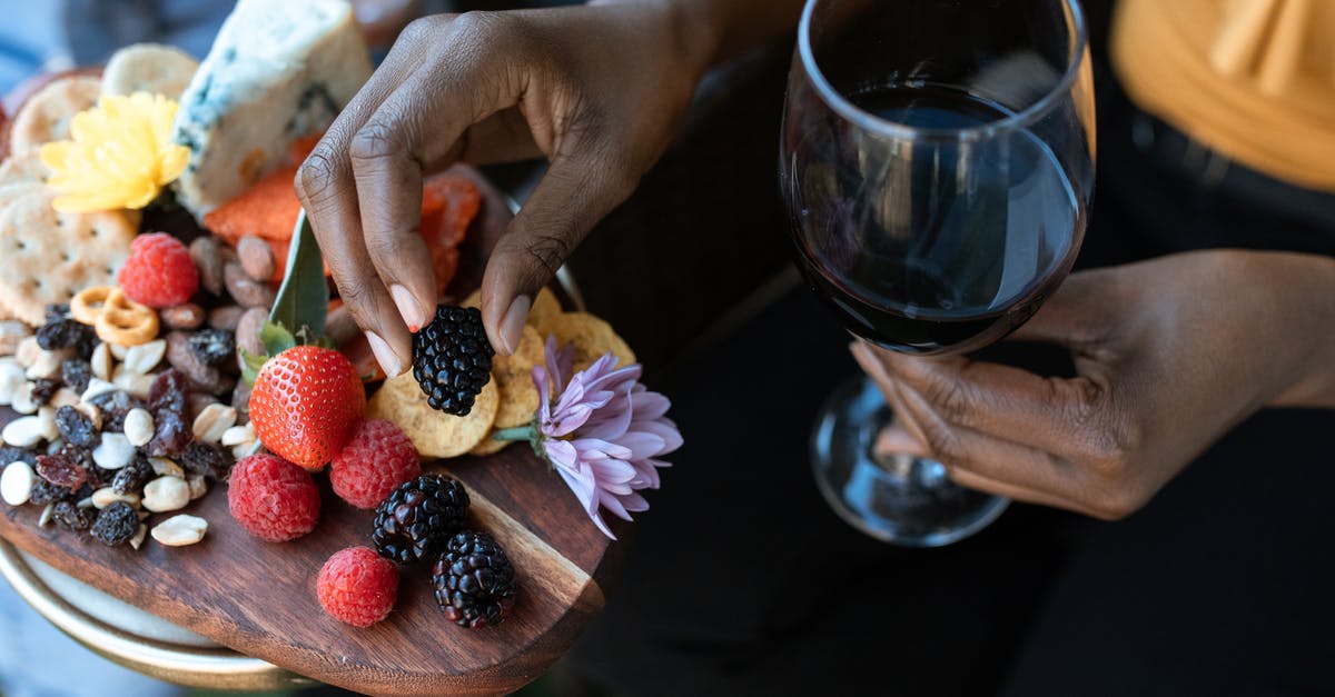 How do I make my cheese "crackers" less greasy? - Hands of Person Holding a Glass of Wine and Blackberry