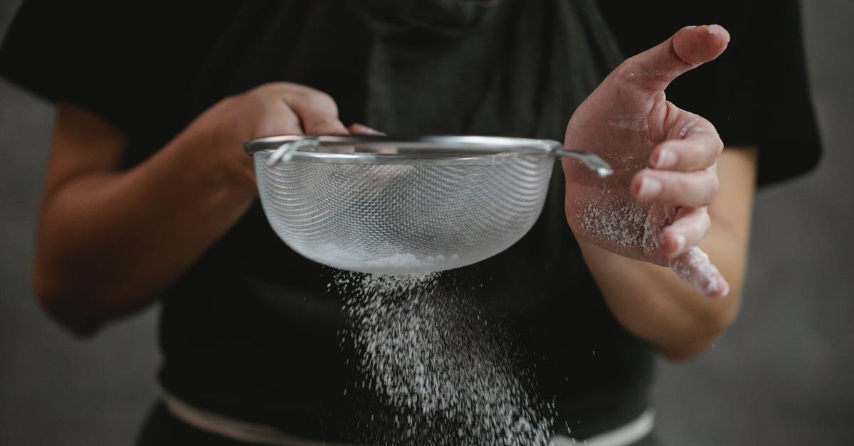 How do I make this no bake tart filling less runny? - Crop anonymous cook in apron sifting flour while preparing baking dish against gray background
