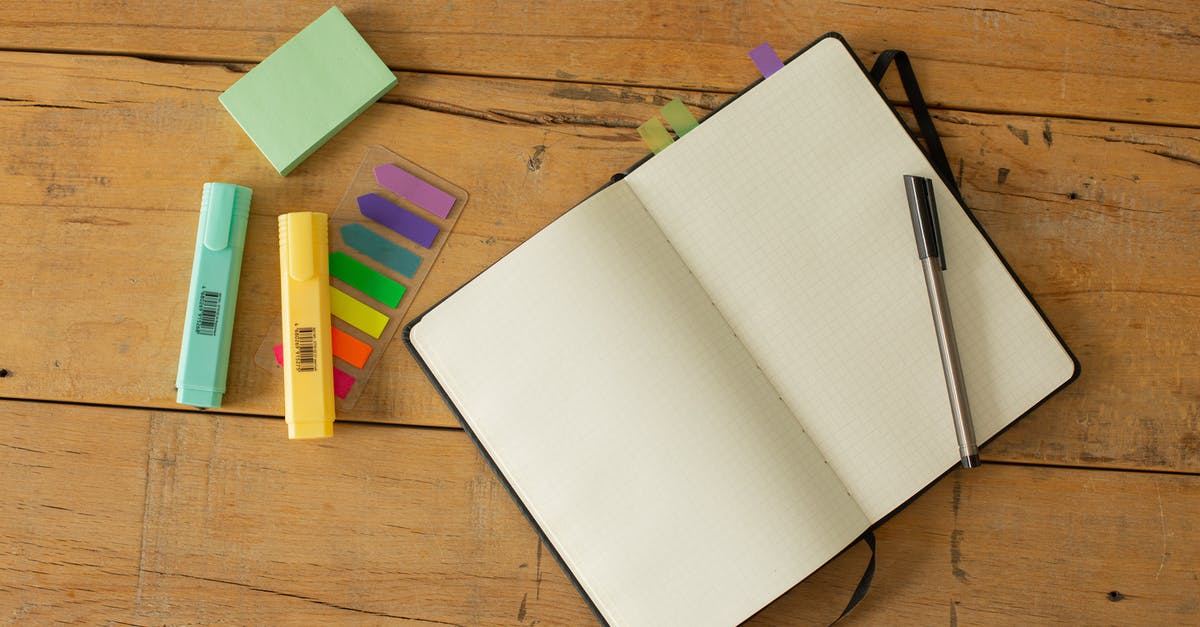 How do I open a brand-new (plug-top) oval canister? - Top view of opened sketchbook with blank pages and pen with coloured markers and bookmarks arranged on wooden desk