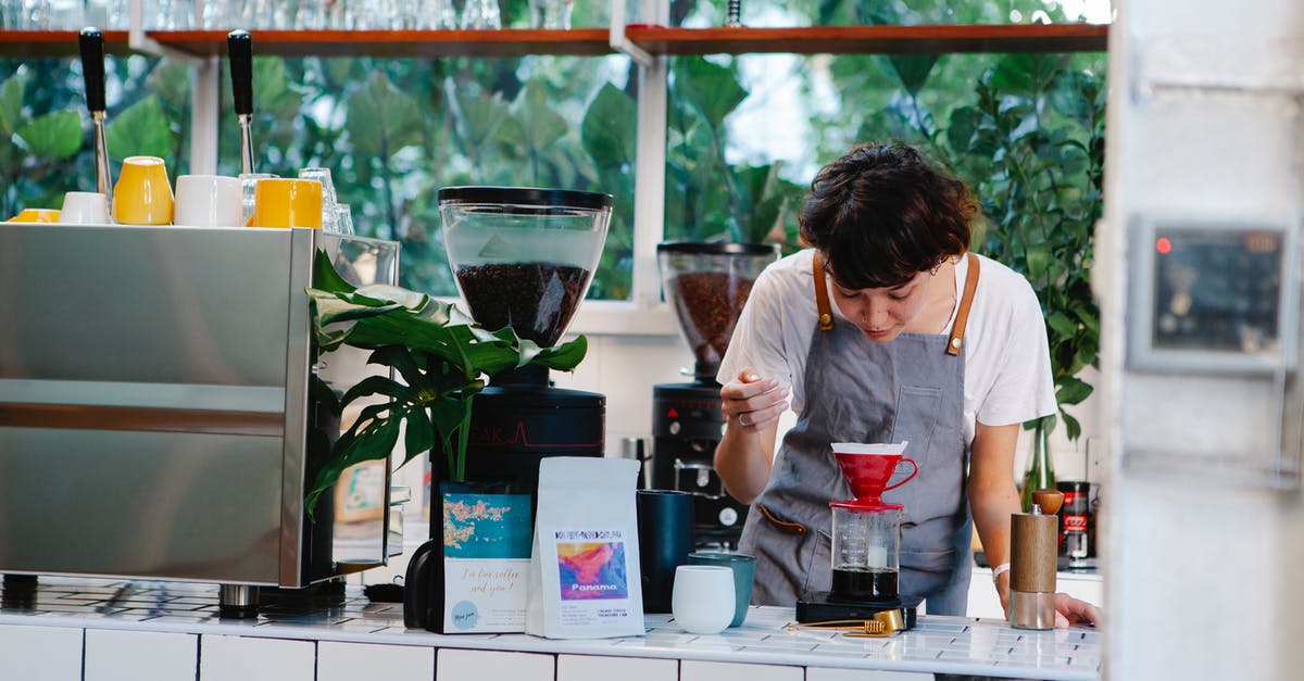 How do I prepare (any) coffee with desired caffeine concentration? - Thoughtful female barista with brown hair in apron pouring aromatic alternative coffee while working in light cafe in daytime