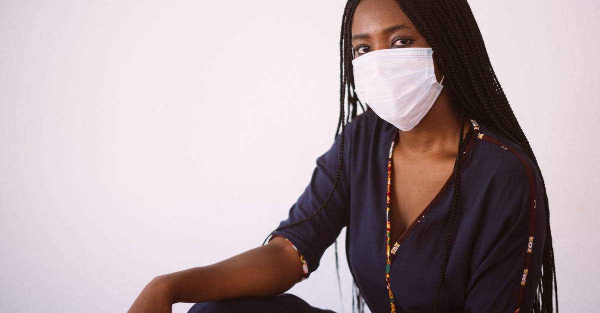 How do I prevent fudge browning? - Side view of unrecognizable African American woman in casual dress and protective mask sitting against gray background looking at camera