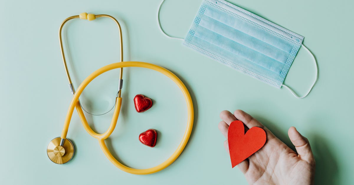 How do I prevent grainy fudge? - Top view of crop anonymous person hand with red paper heart on table with stethoscope and medical mask for coronavirus prevention