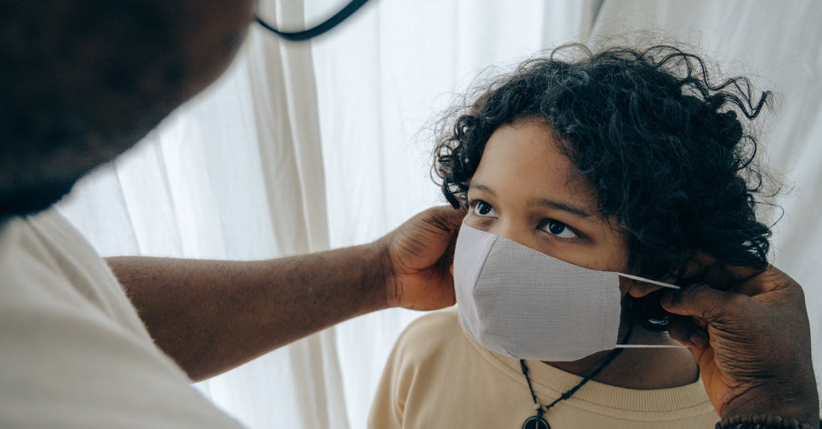 How do I prevent smoke problems indoors? - From above unrecognizable black man wearing protective mask on face of ethnic kid standing in room near window closed with curtain