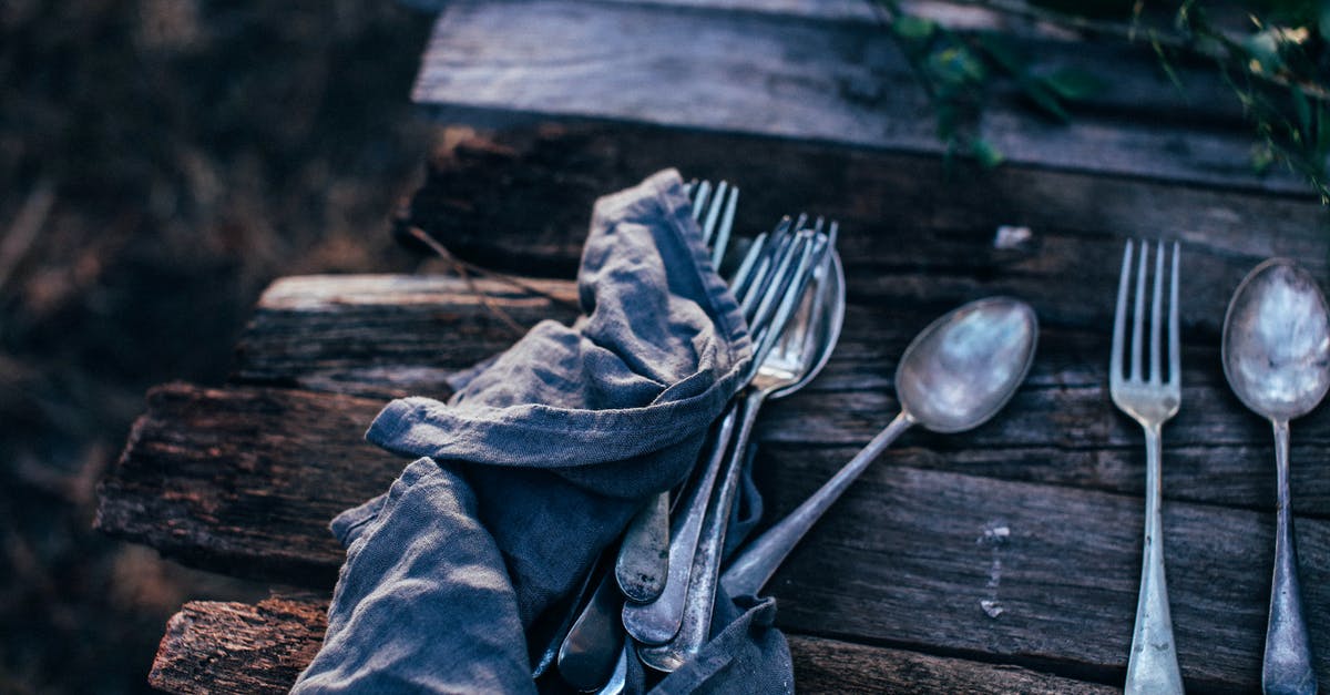 How do I remove boar taint (from a wooden handle)? - High angle of spoons with forks near crumpled textile on rustic table in garden on sunny day