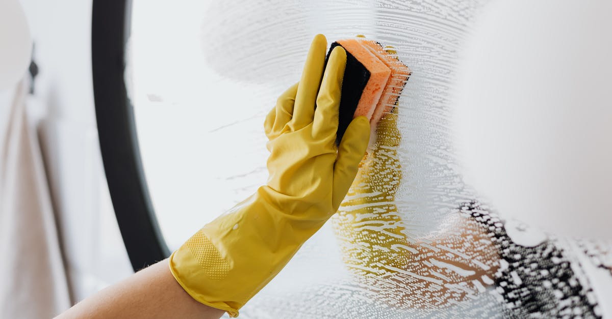 How do I remove my KitchenAid attachment? - Anonymous person in yellow rubber gloves using simple sponge for cleaning mirror in bathroom