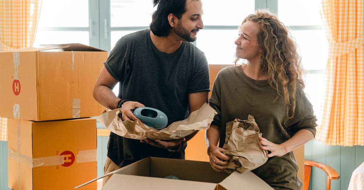 How do I separate crackers stuck to parchment paper? - Multiethnic couple packing ceramic belongings in parchment before relocation