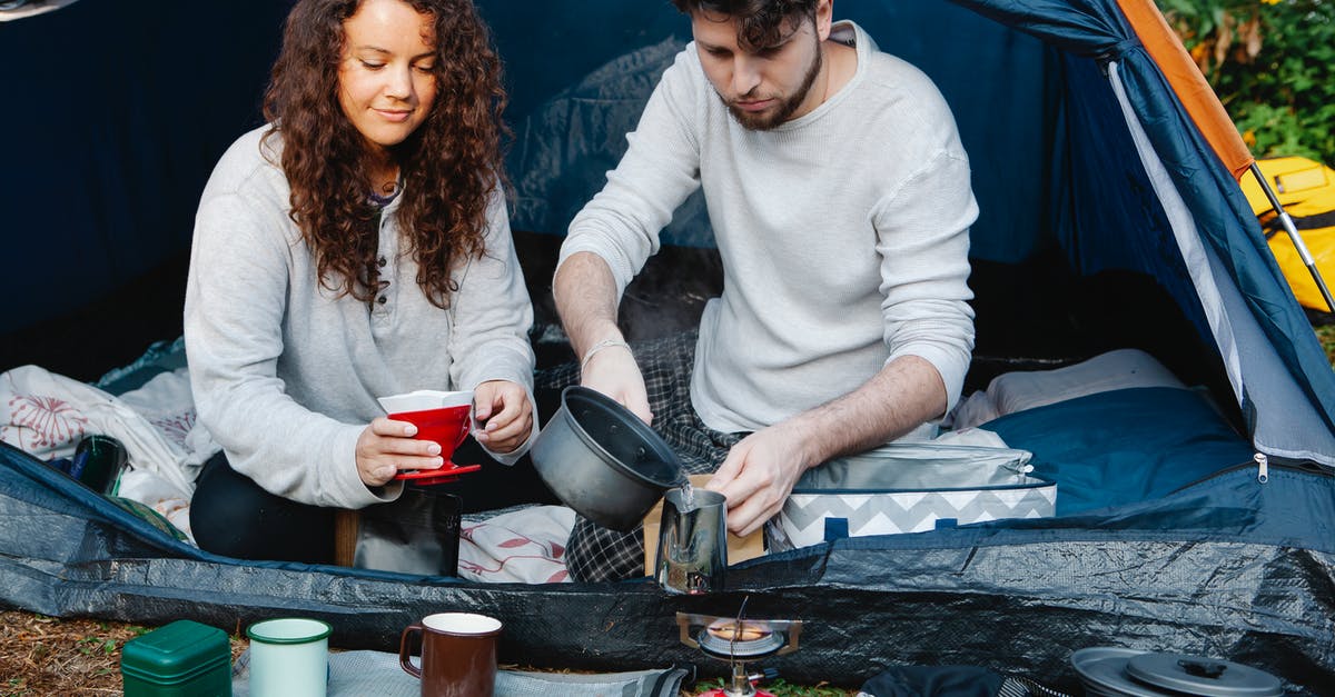 How do I stop metal-bottomed pots squeaking on my gas hob? - Crop couple of travelers preparing coffee in tent