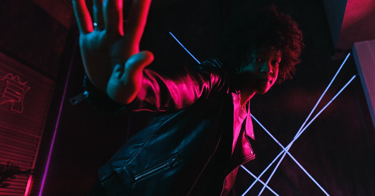 How do I stop my pans from boiling over? - Low angle of trendy black female adolescent leaning forward while demonstrating control gesture and looking at camera against lamps at night