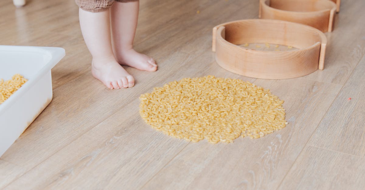 How do I tell bucatelli pasta size and thickness - Crop faceless toddler standing barefoot on floor and playing with round wooden shapes of different size and pasta developing fine motor skills at home