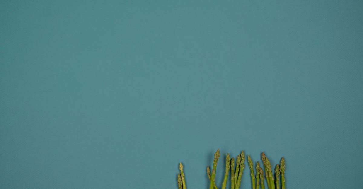 How do I tone down the intensity of raw onion? - Top view of raw asparagus stalks with ribbed surface in row on green background